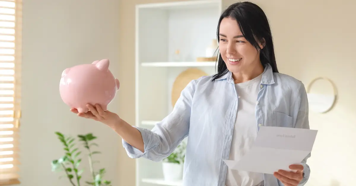 A smiling woman displays a piggy bank and a letter, symbolizing savings and financial planning.